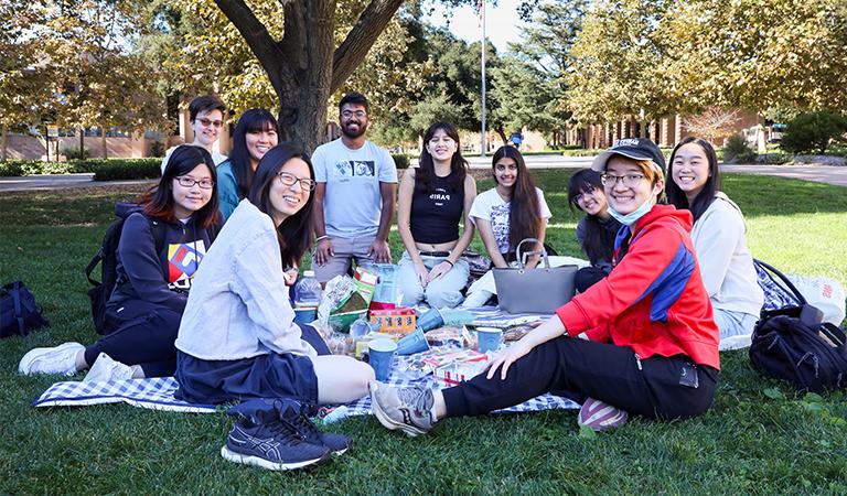 项目连接的学生聚集在草坪上野餐下午.